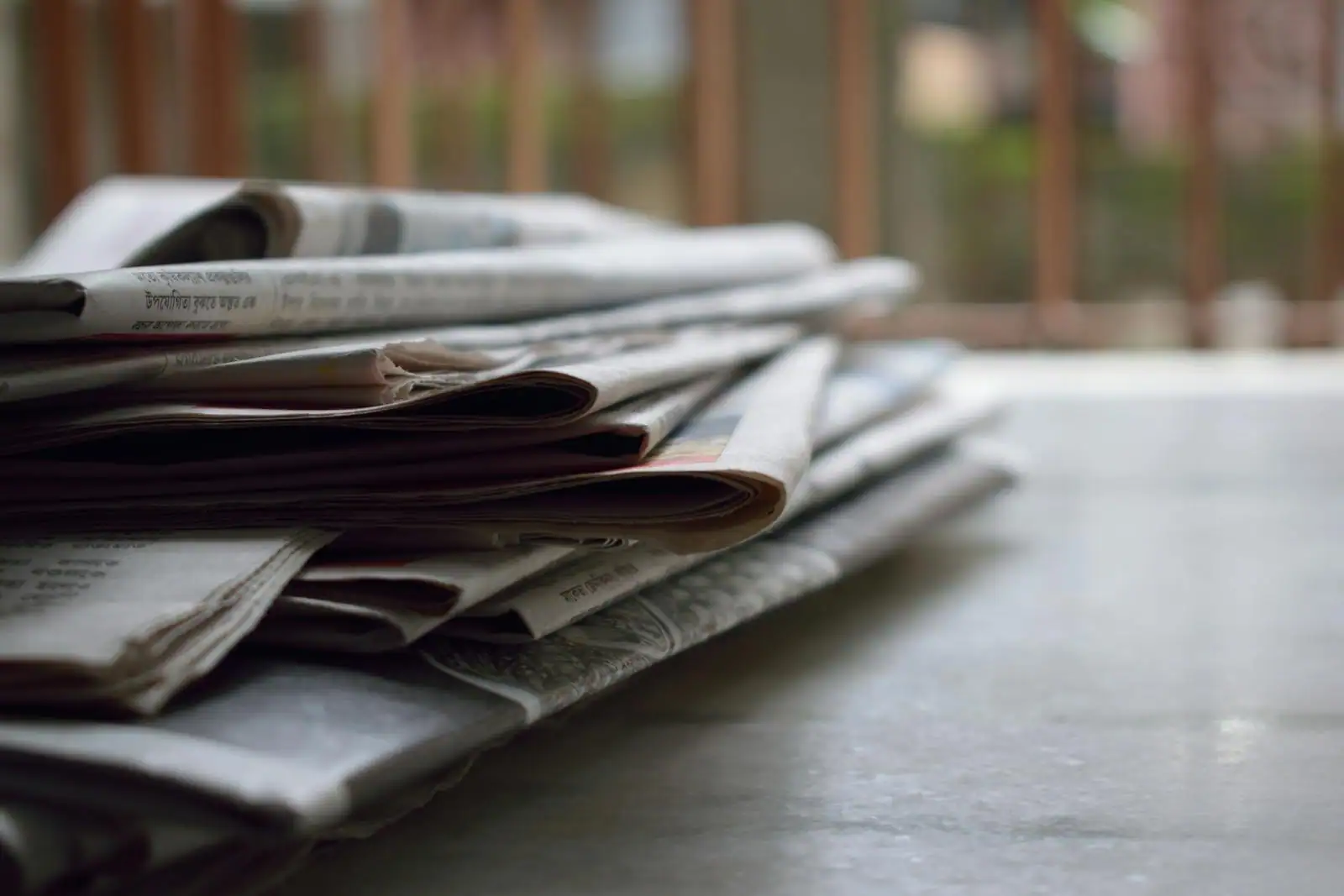 Écrans de cotation et journaux économiques posés sur une table, ambiance sobre de bureau de veille.