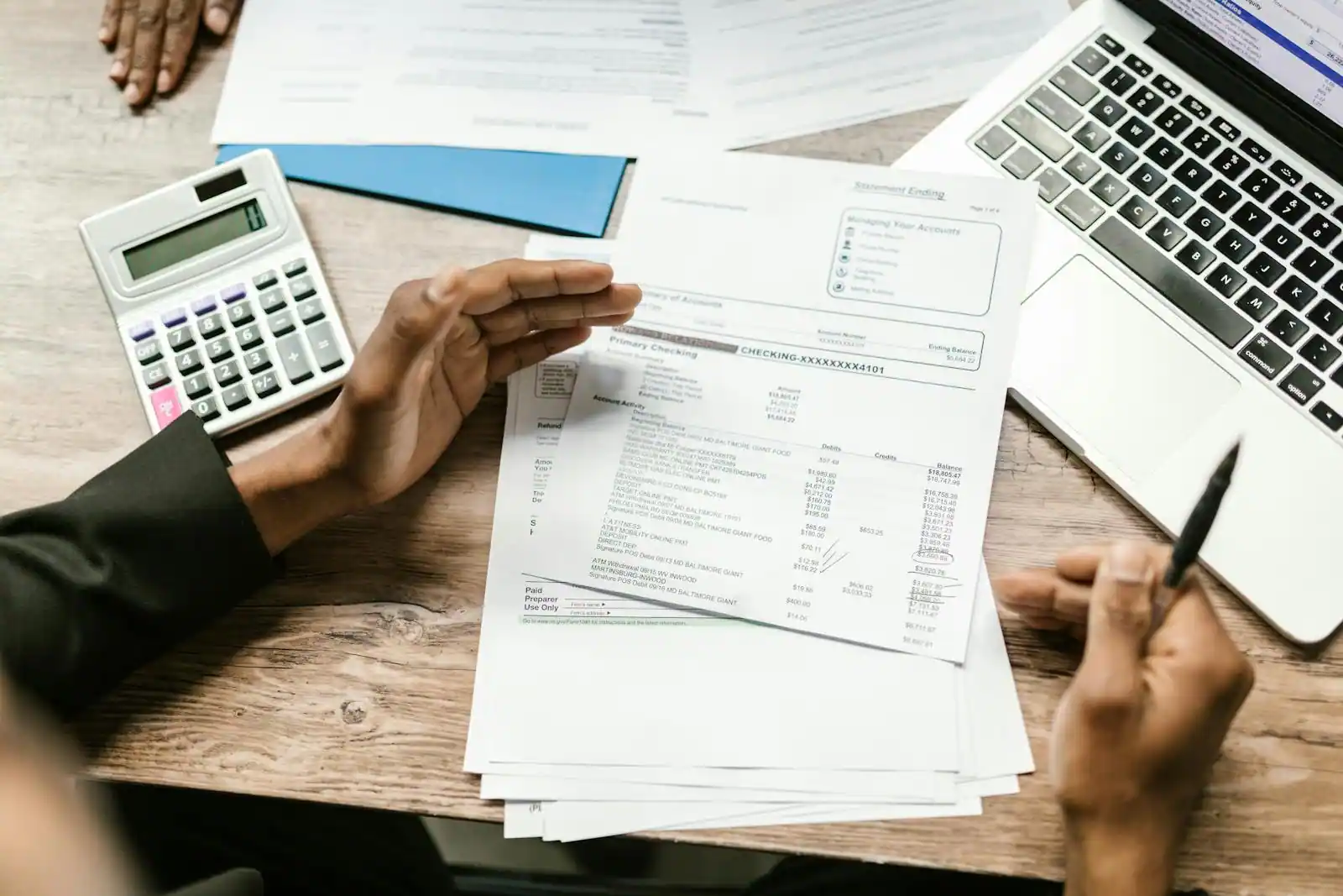 Dirigeant de TPE signant des documents bancaires professionnels sur un bureau de banque