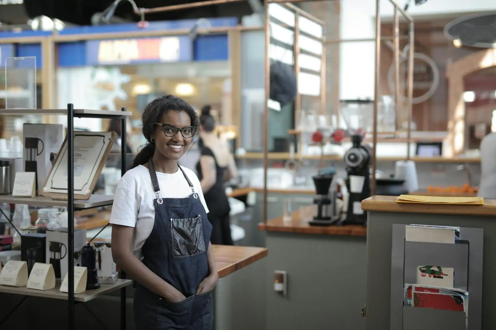 Jeune entrepreneuse souriante derrière le comptoir de son commerce récemment ouvert