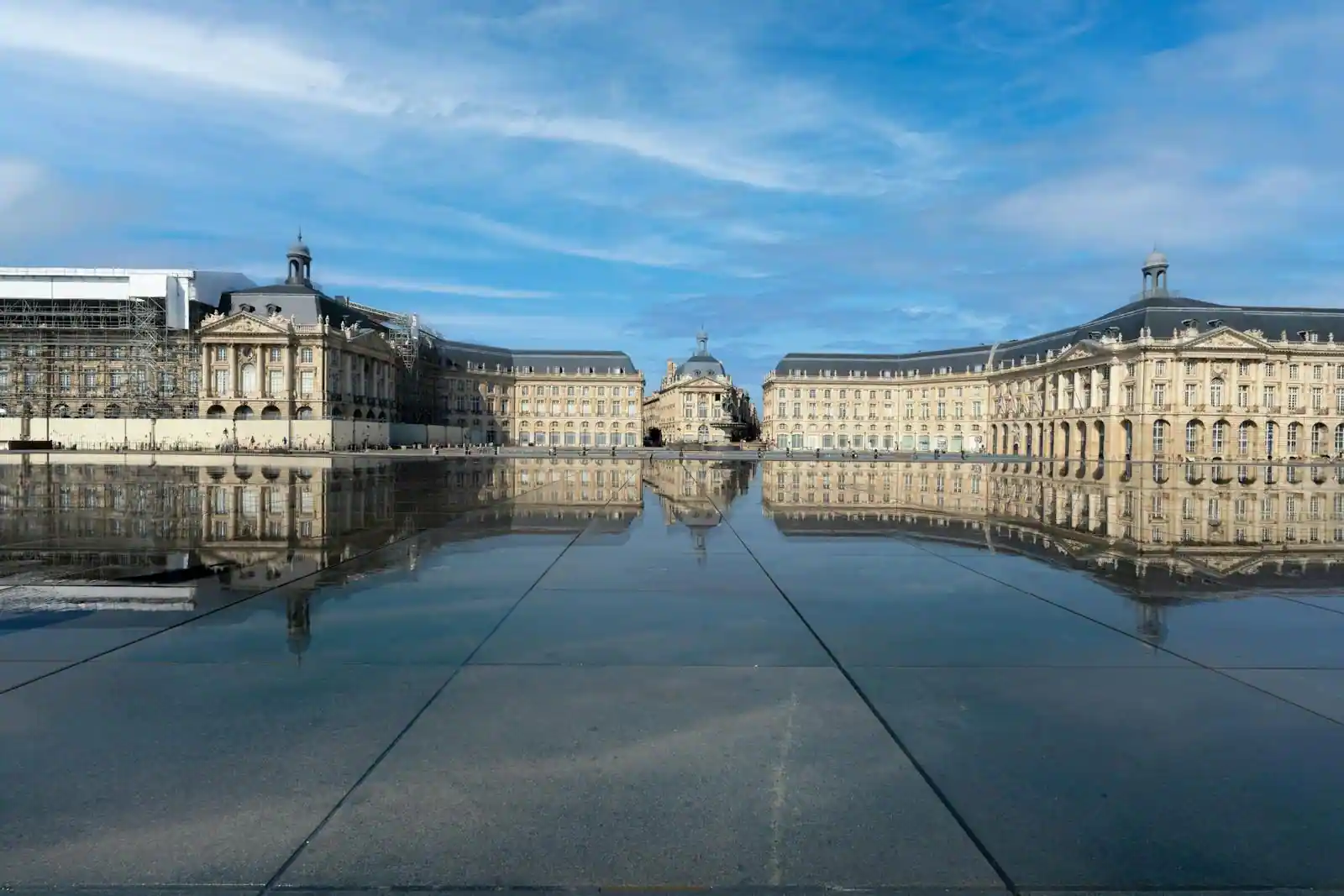 Vue aérienne des quais de Bordeaux le long de la Garonne, avec le miroir d'eau et la place de la Bourse au soleil