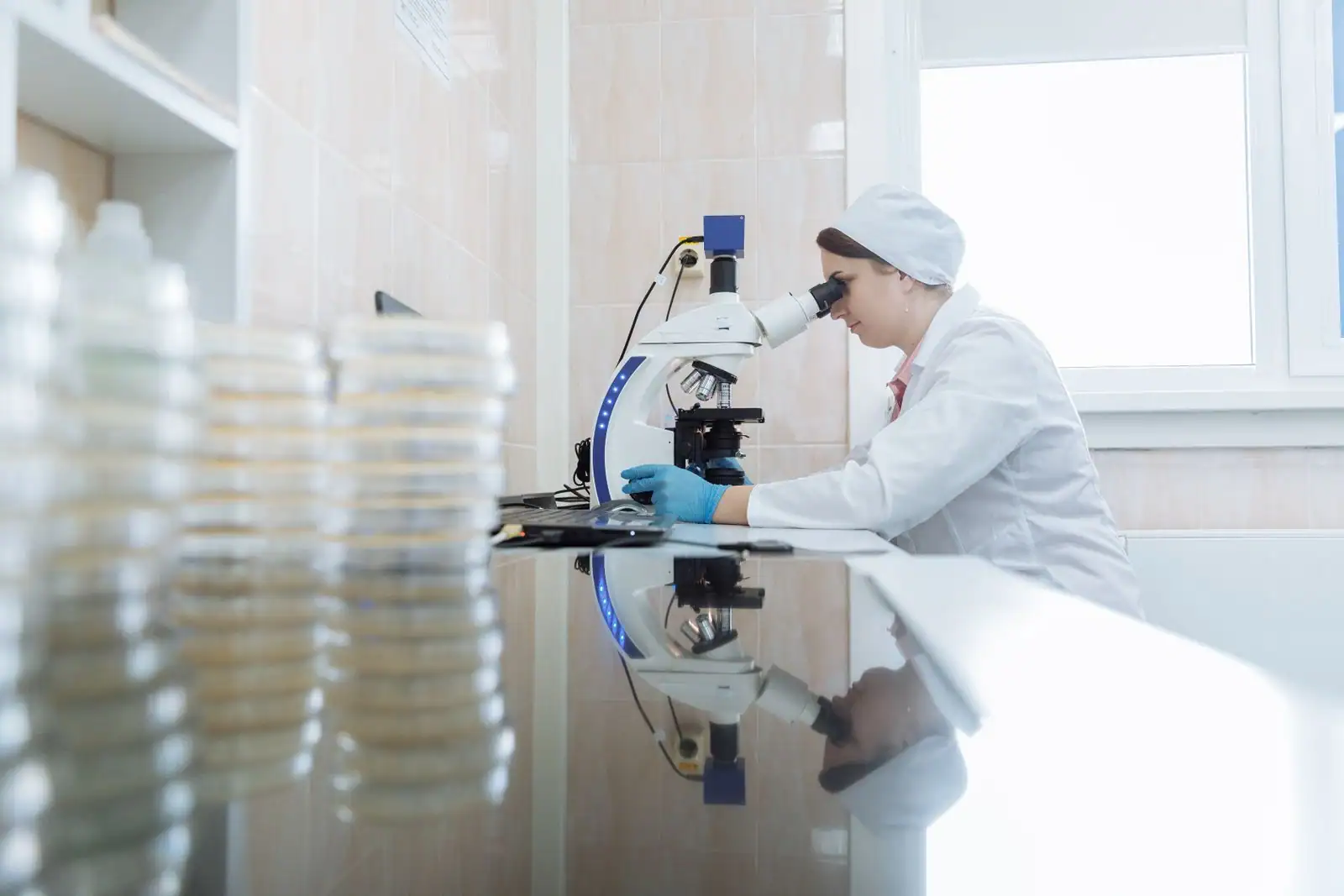 Scientifique en blouse blanche observant au microscope dans un laboratoire de recherche