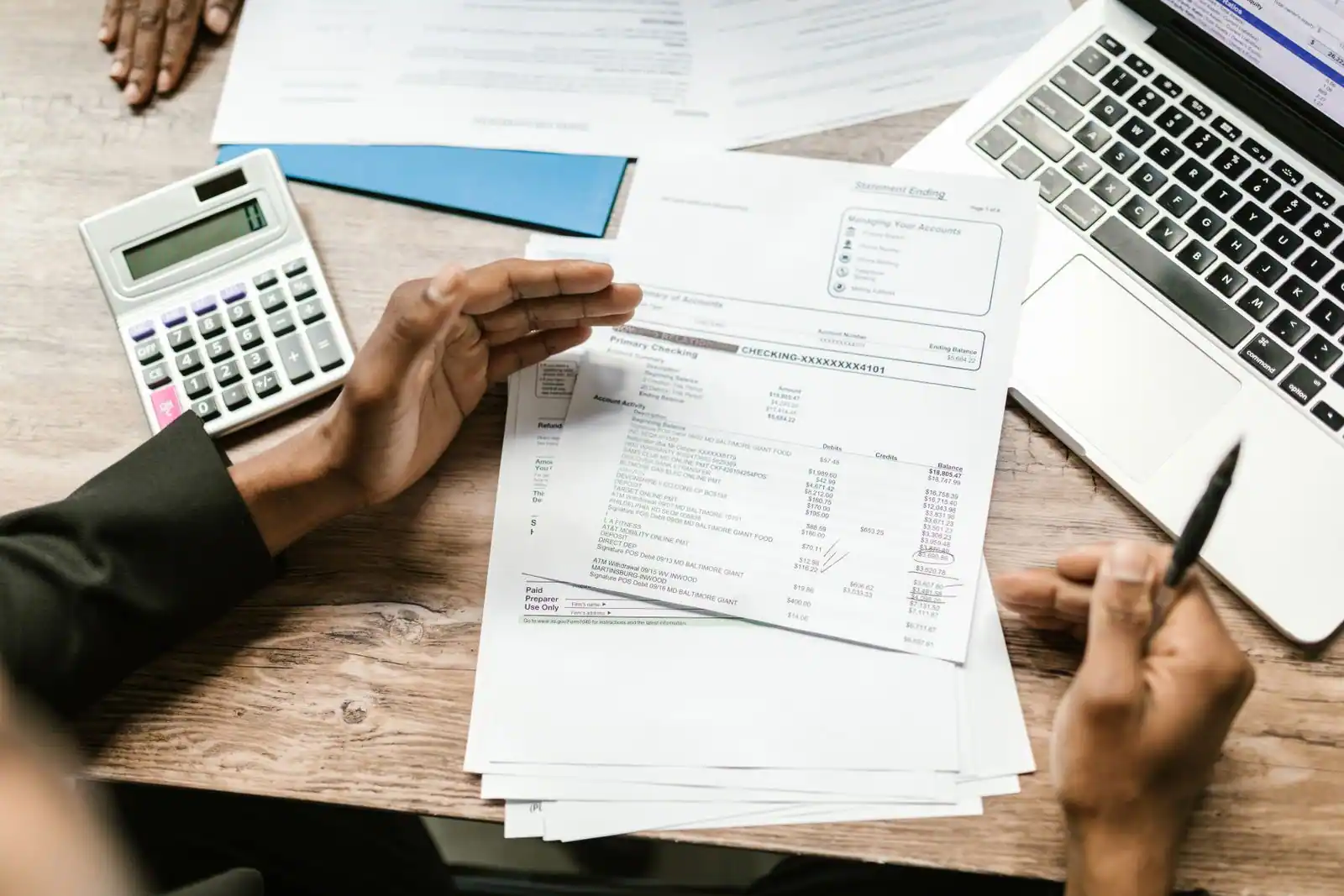 Calculatrice, documents administratifs et ordinateur portable sur un bureau, pour gérer la fiscalité de son activité.