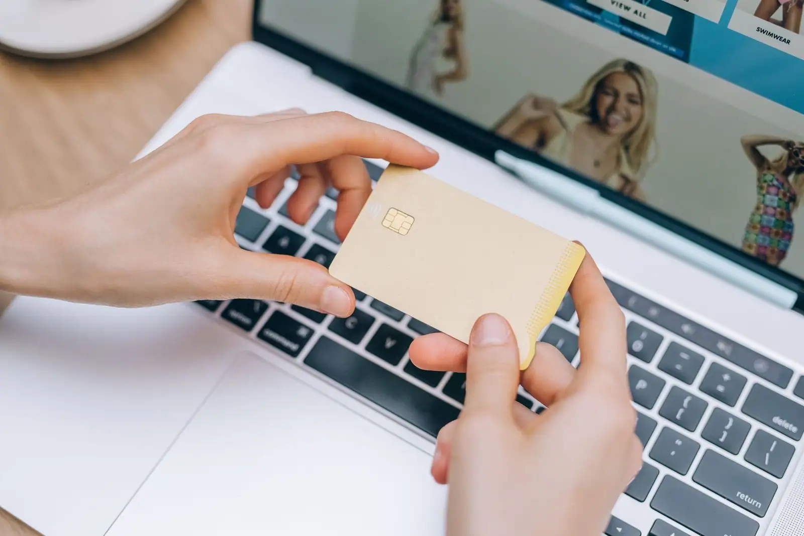Mains tenant une carte bancaire devant un ordinateur portable, illustration de la banque en ligne