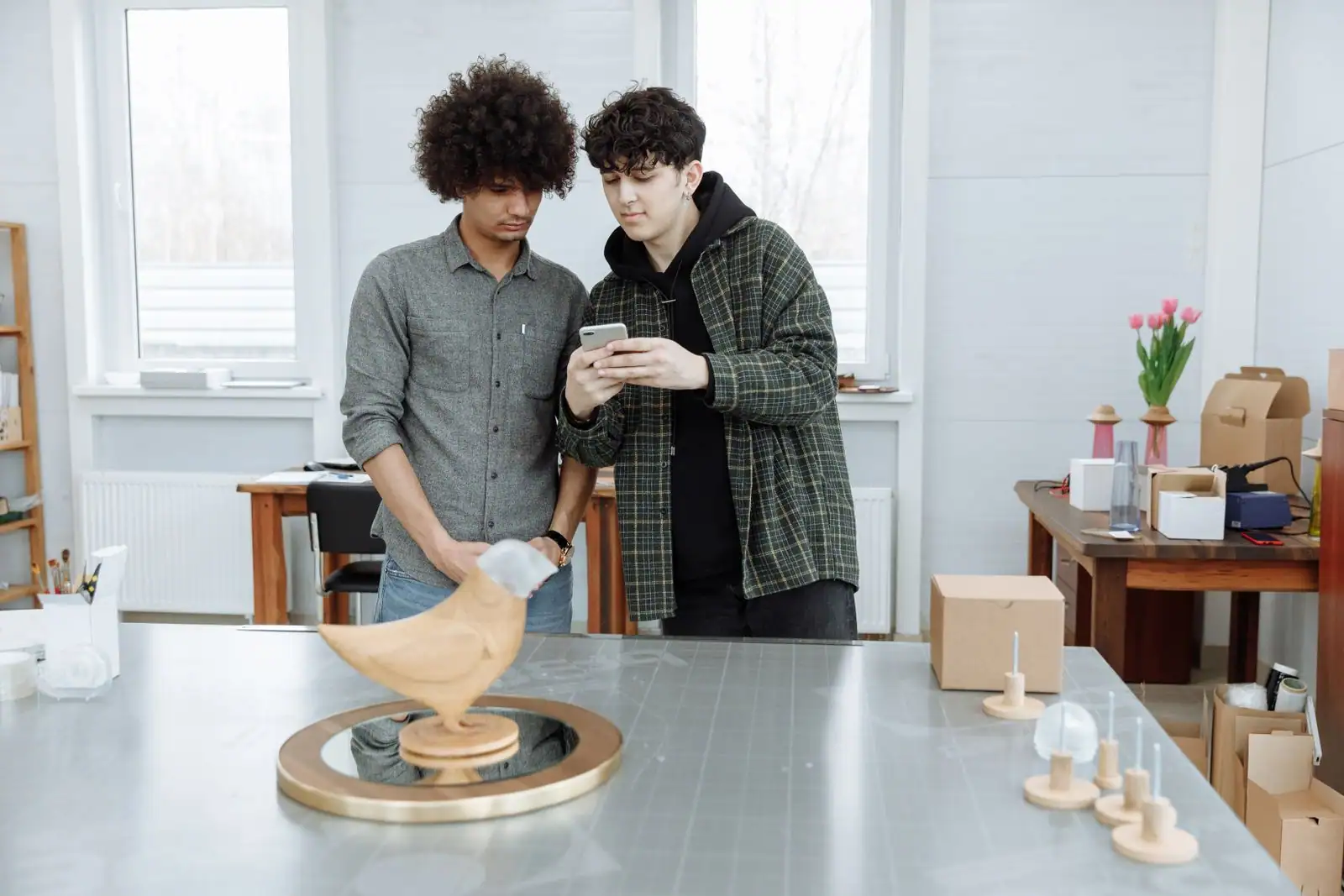 Deux jeunes entrepreneurs au travail dans leur atelier, autour de produits et d'emballages