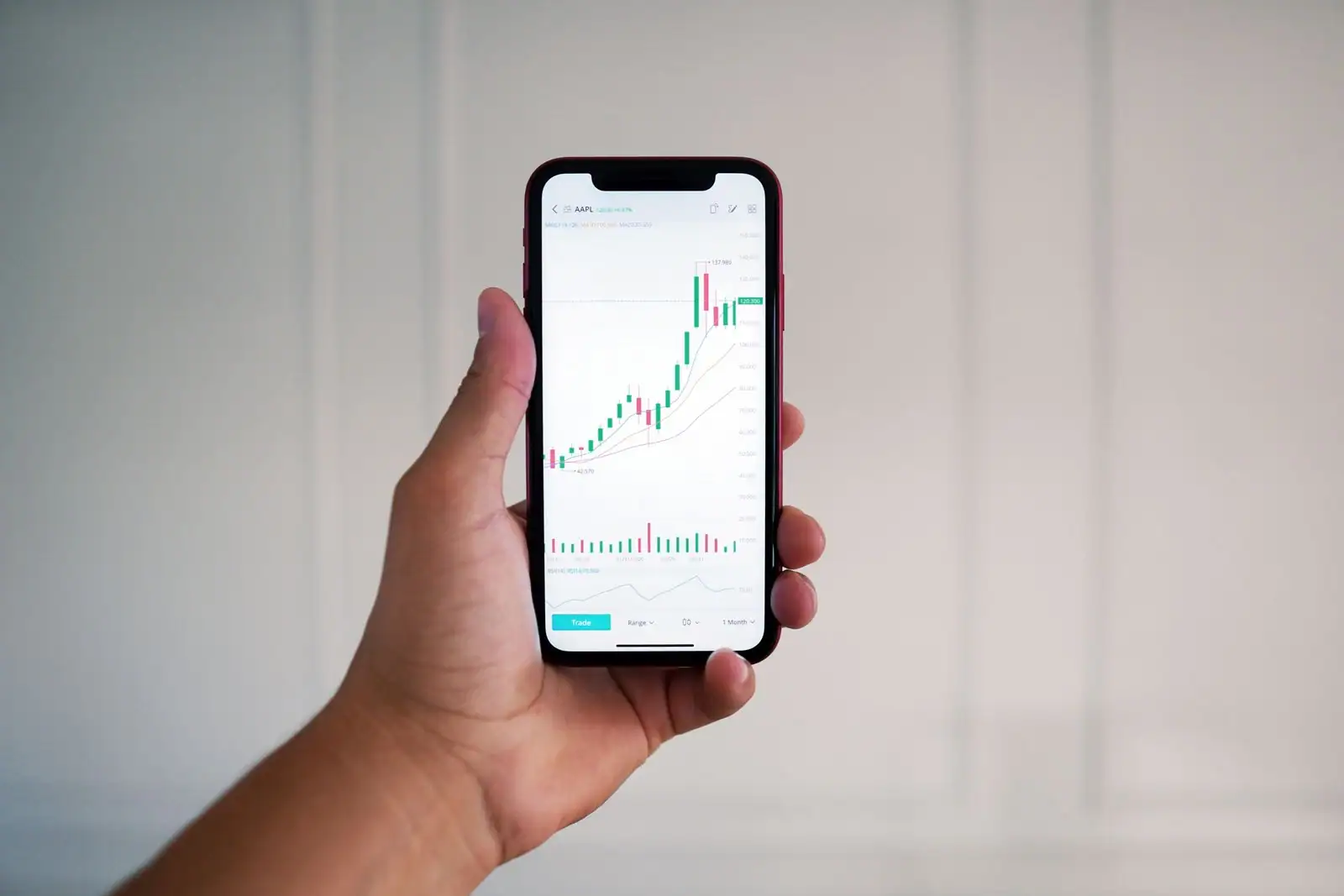 Smartphone tenu en main affichant une application de suivi des cours de Bourse avec un graphique