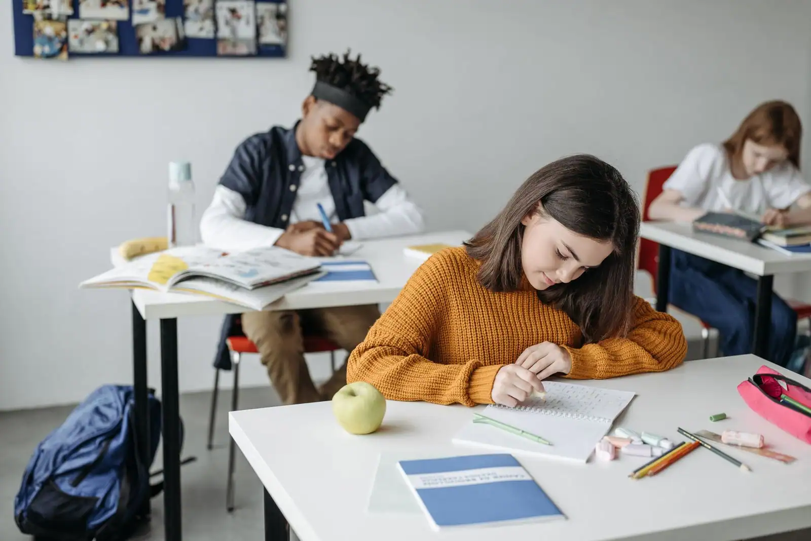 Élèves au travail dans une salle de classe, au premier plan une lycéenne écrivant dans son cahier.
