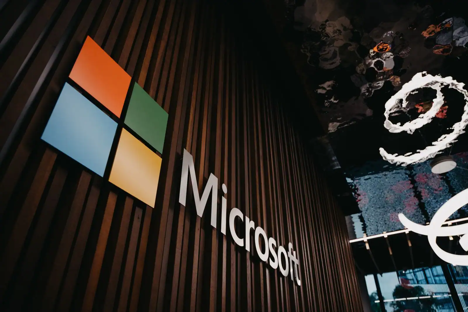 Logo et nom de Microsoft fixés sur un mur en lattes de bois dans un espace de bureaux