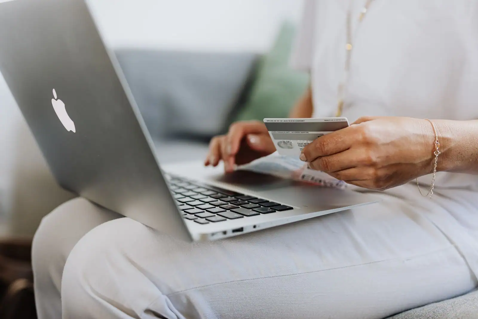 Personne utilisant un ordinateur portable et tenant une carte bancaire, pour la banque en ligne.
