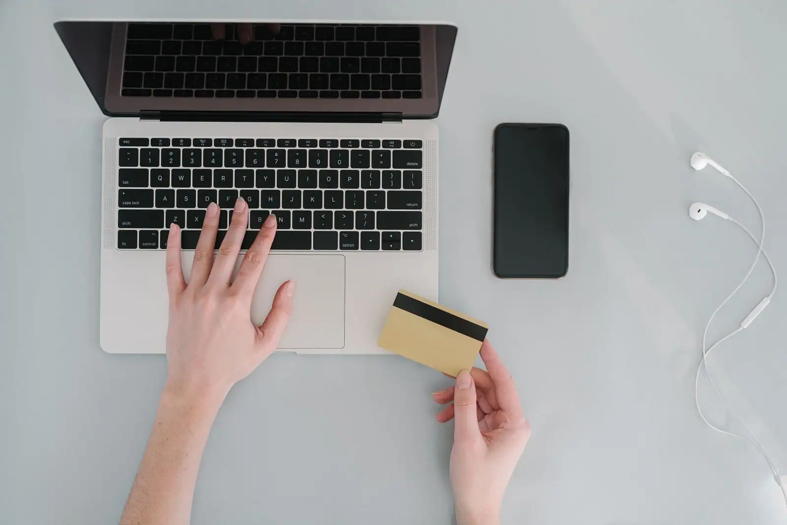 Mains utilisant un ordinateur portable et une carte bancaire pour une opération en ligne, smartphone à côté