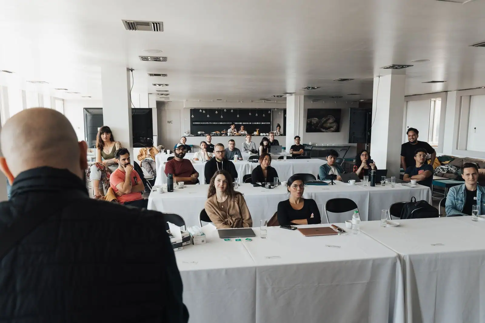 Intervenant s'adressant à une assistance lors d'un événement professionnel en salle.