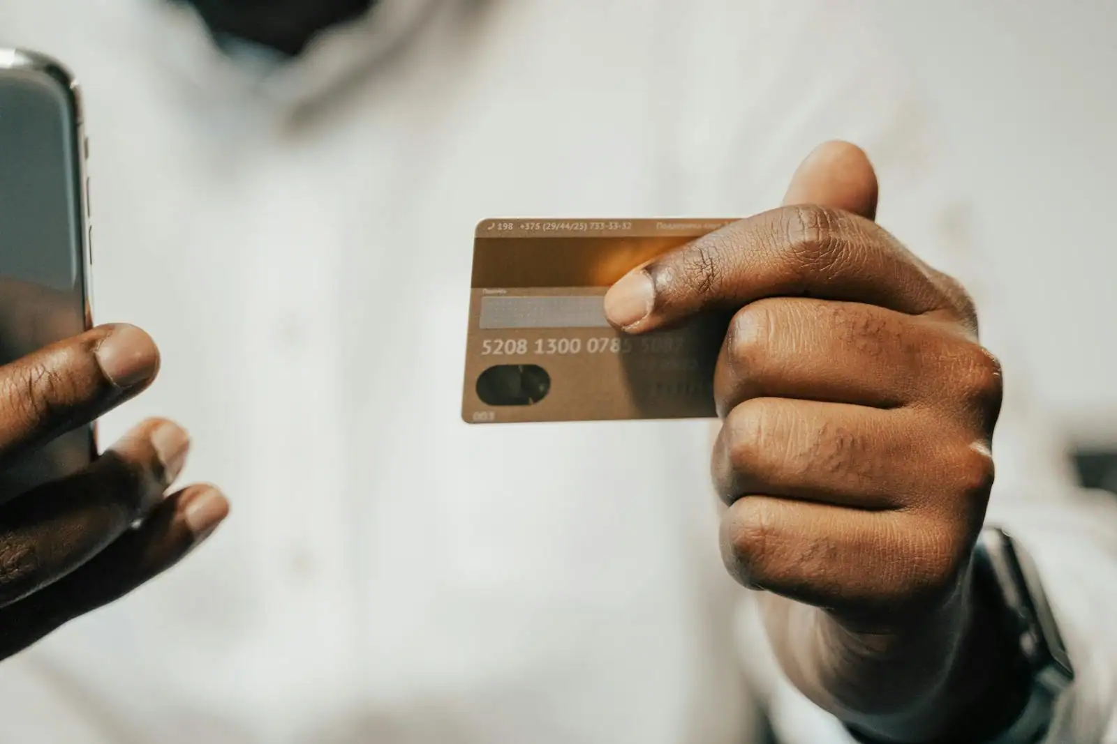 Gros plan sur des mains tenant une carte de paiement et un smartphone.