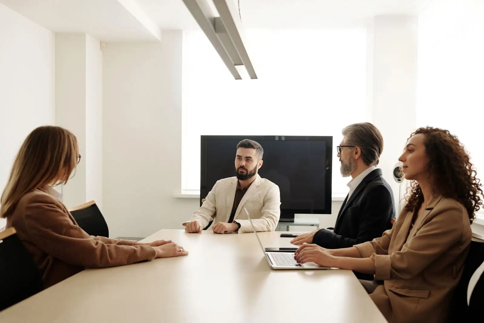 Quatre professionnels en réunion autour d'une table dans des bureaux d'entreprise lumineux
