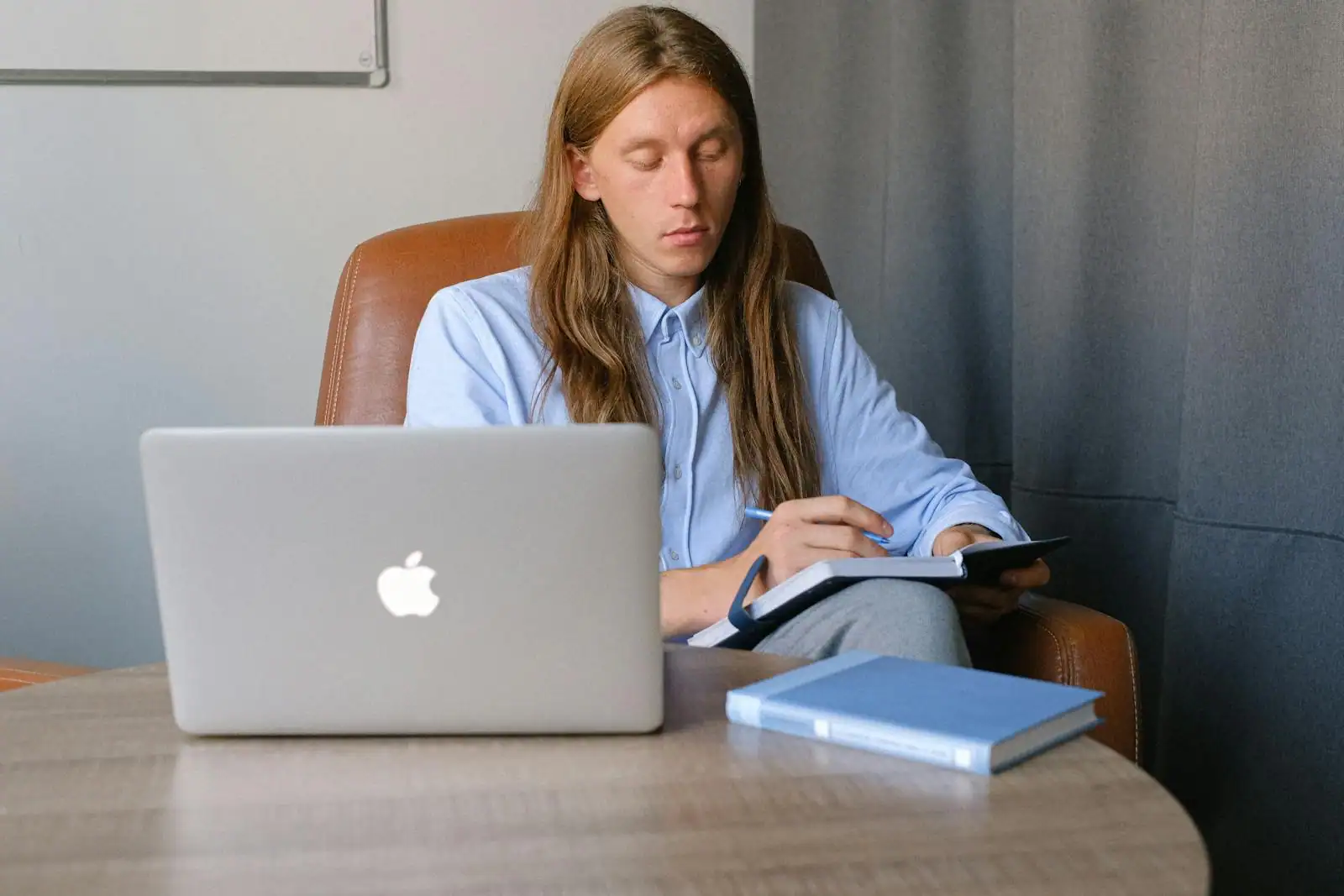 Homme concentré travaillant sur un ordinateur portable et prenant des notes à un bureau