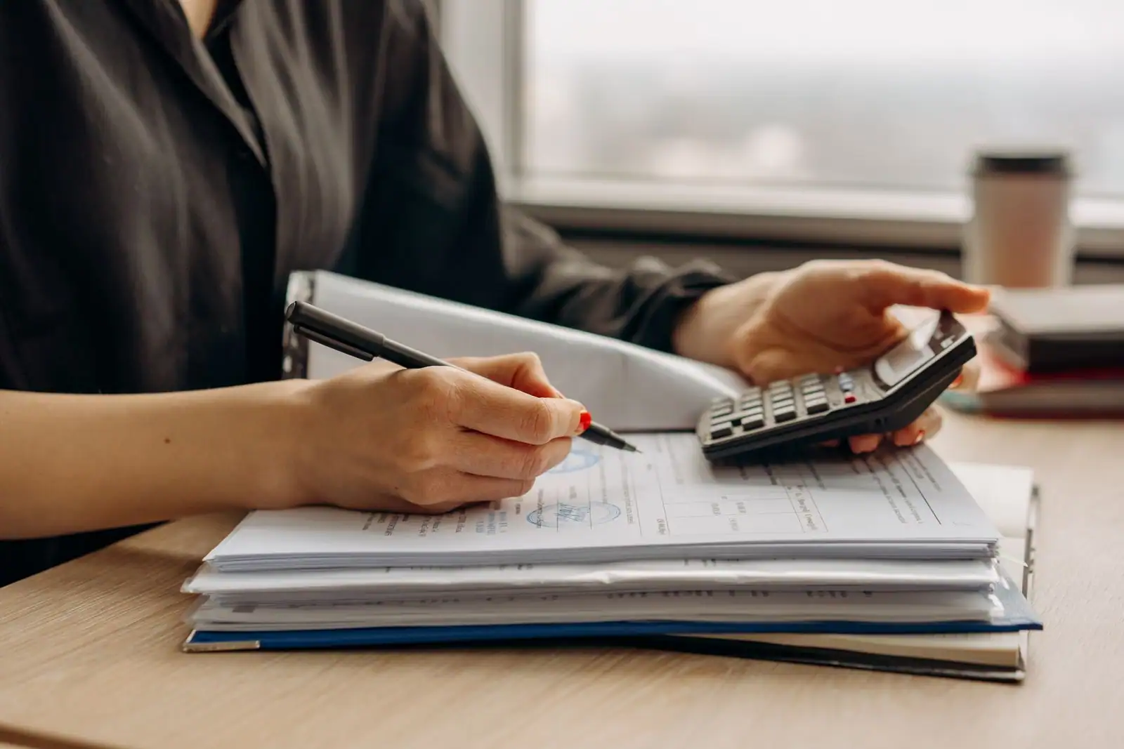 Personne organisant des documents financiers sur un bureau
