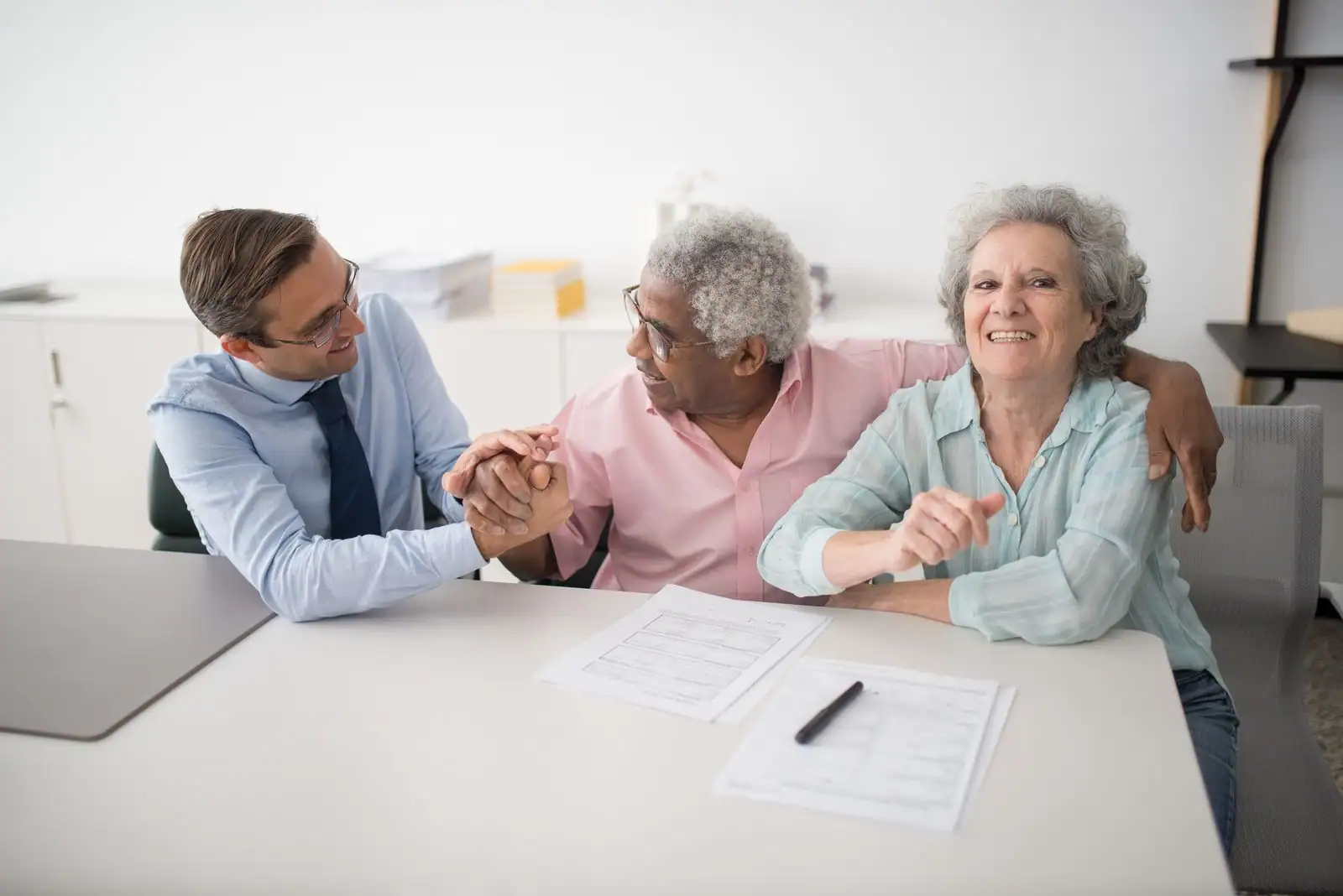 Conseiller en gestion de patrimoine accueillant un couple de clients autour de documents financiers