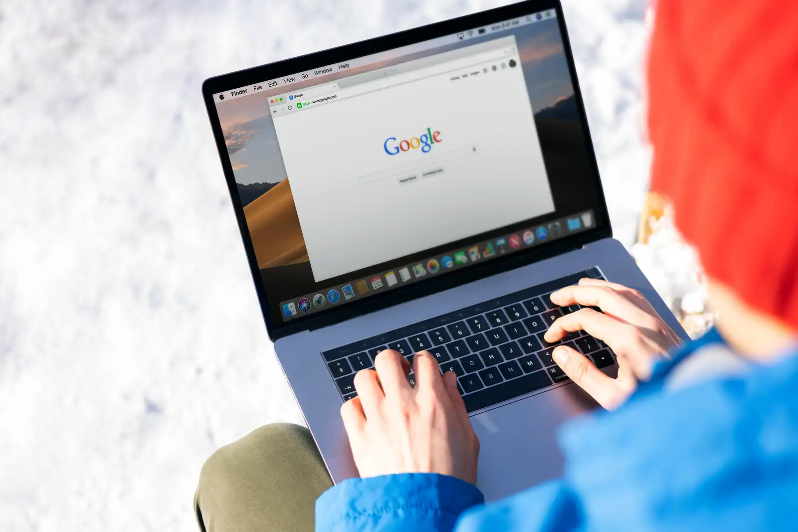 Personne effectuant une recherche en ligne sur un ordinateur portable affichant un moteur de recherche