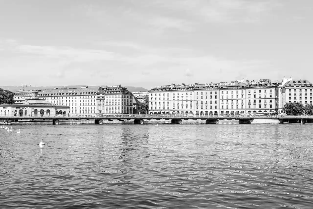 Front de lac d'une ville suisse, en noir et blanc, avec ses façades d'immeubles alignées le long du quai