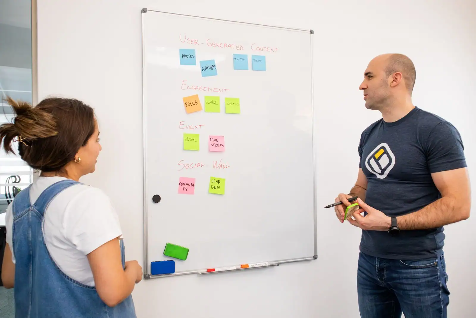 Réunion de travail autour d'une stratégie de communication : tableau, notes et échanges entre collègues.