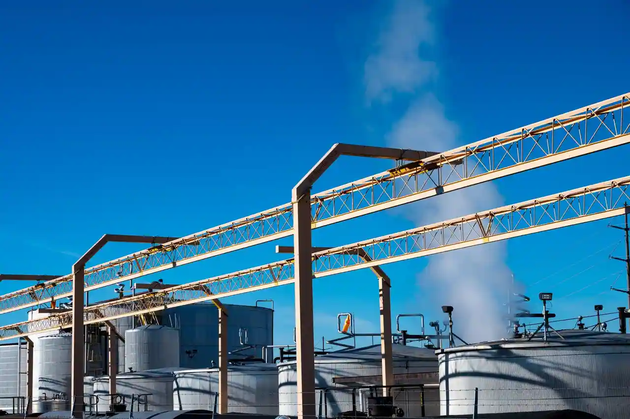 Site industriel avec cuves de stockage métalliques et passerelles de tuyauteries, sous un ciel dégagé.