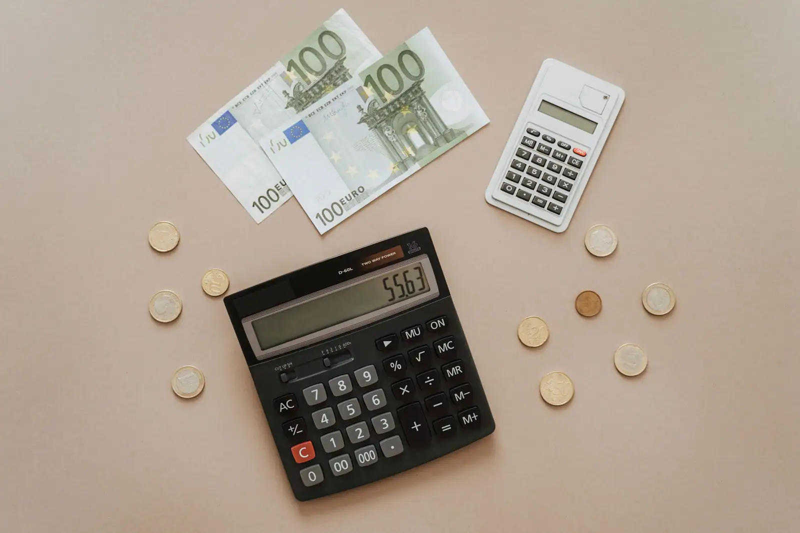 Billets et pièces en euros posés à côté de calculatrices, illustration du calcul des impôts et des finances.