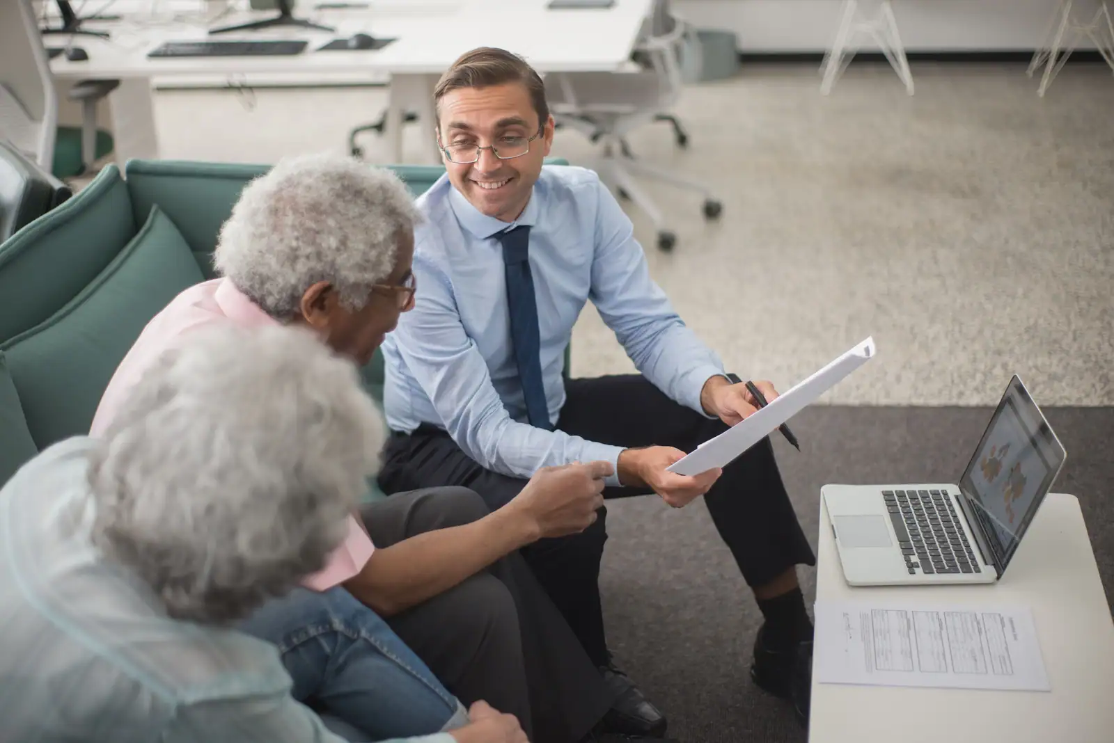 Un conseiller présente un document à un couple de clients lors d'un rendez-vous financier au bureau.