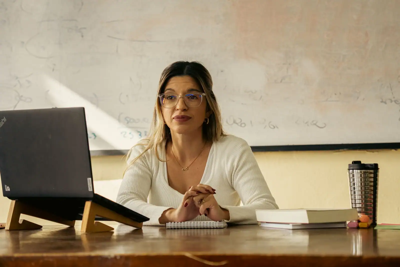 Enseignant à son bureau avec ordinateur portable et documents, préparant le suivi de ses élèves.