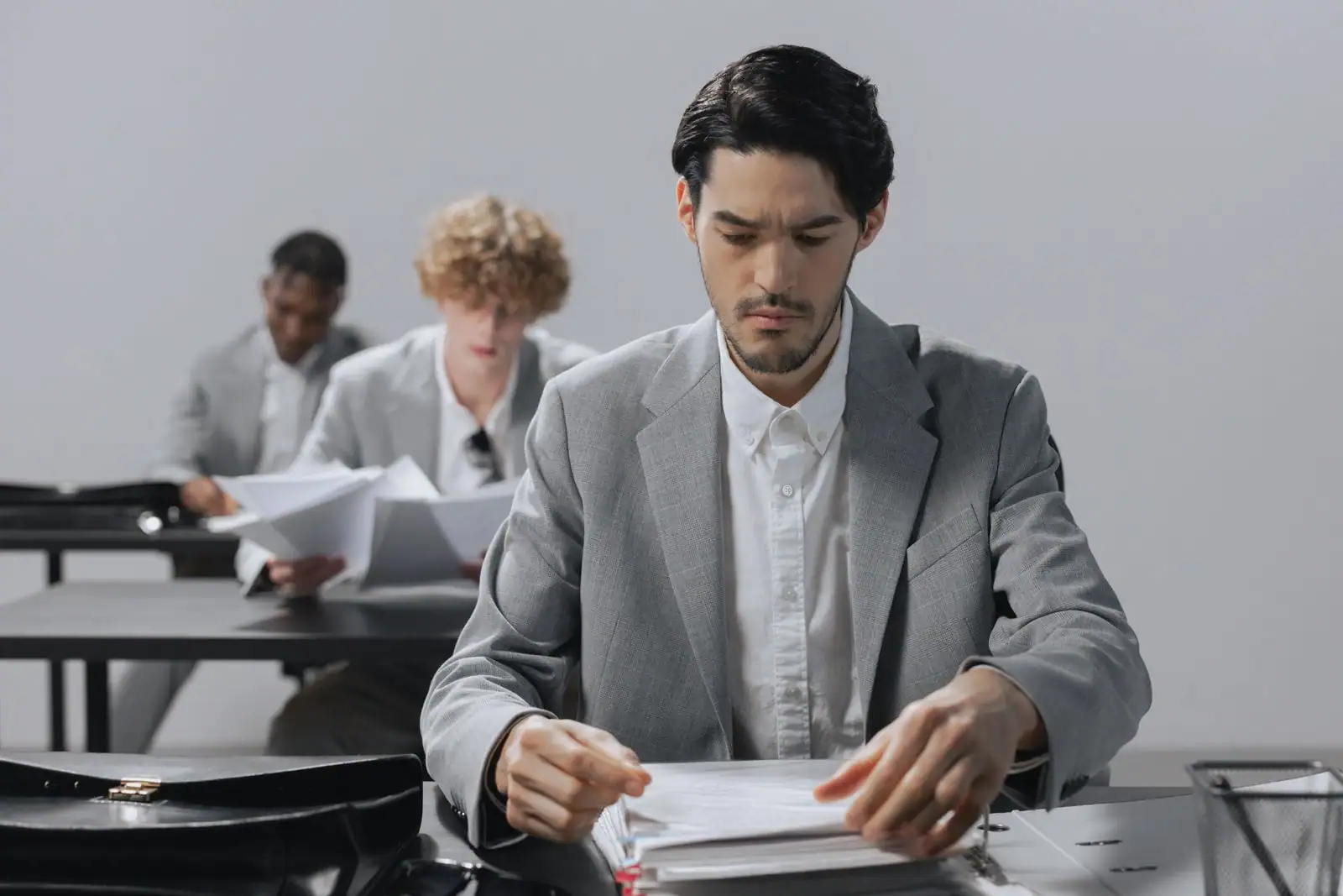 Un professionnel trie des documents administratifs à son bureau, dans un espace de travail partagé.