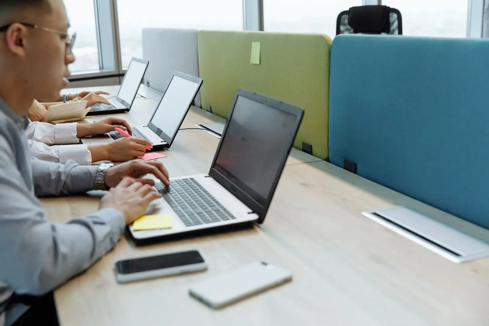 Plusieurs personnes travaillent sur des ordinateurs portables dans un espace de coworking ouvert.