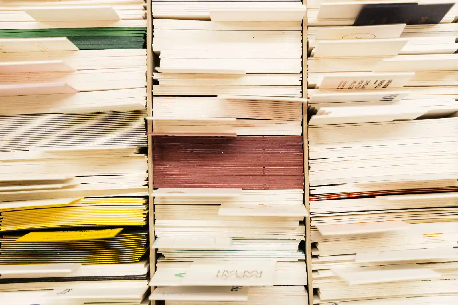 Des piles de formulaires et de dossiers administratifs rangés dans des casiers de classement.