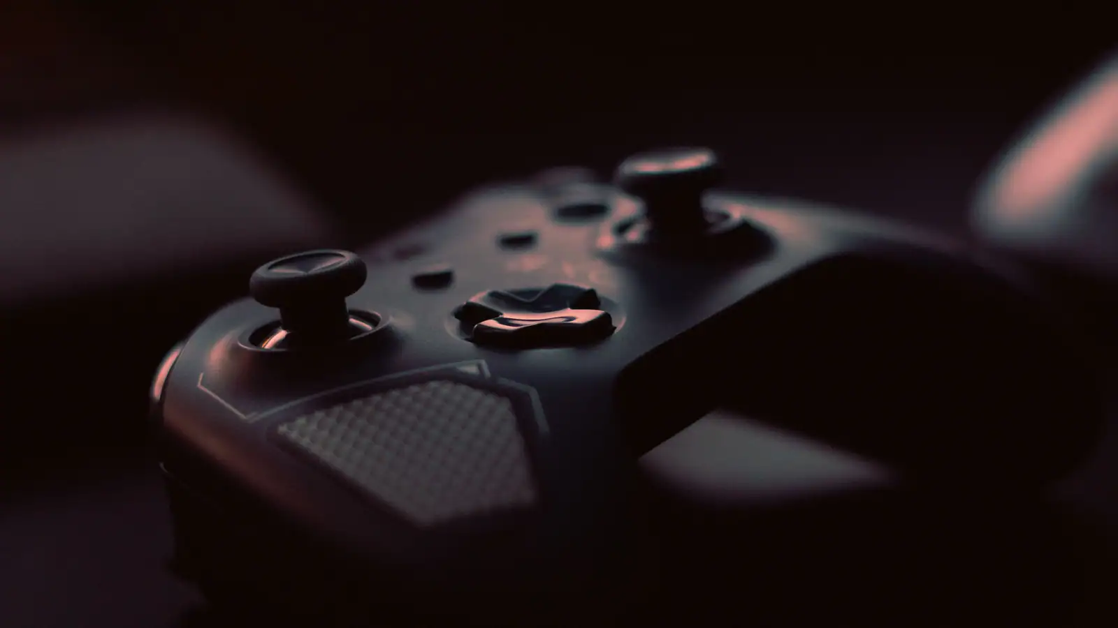 Gros plan sur une manette de jeu posée dans la pénombre, éclairée par une lumière rasante.