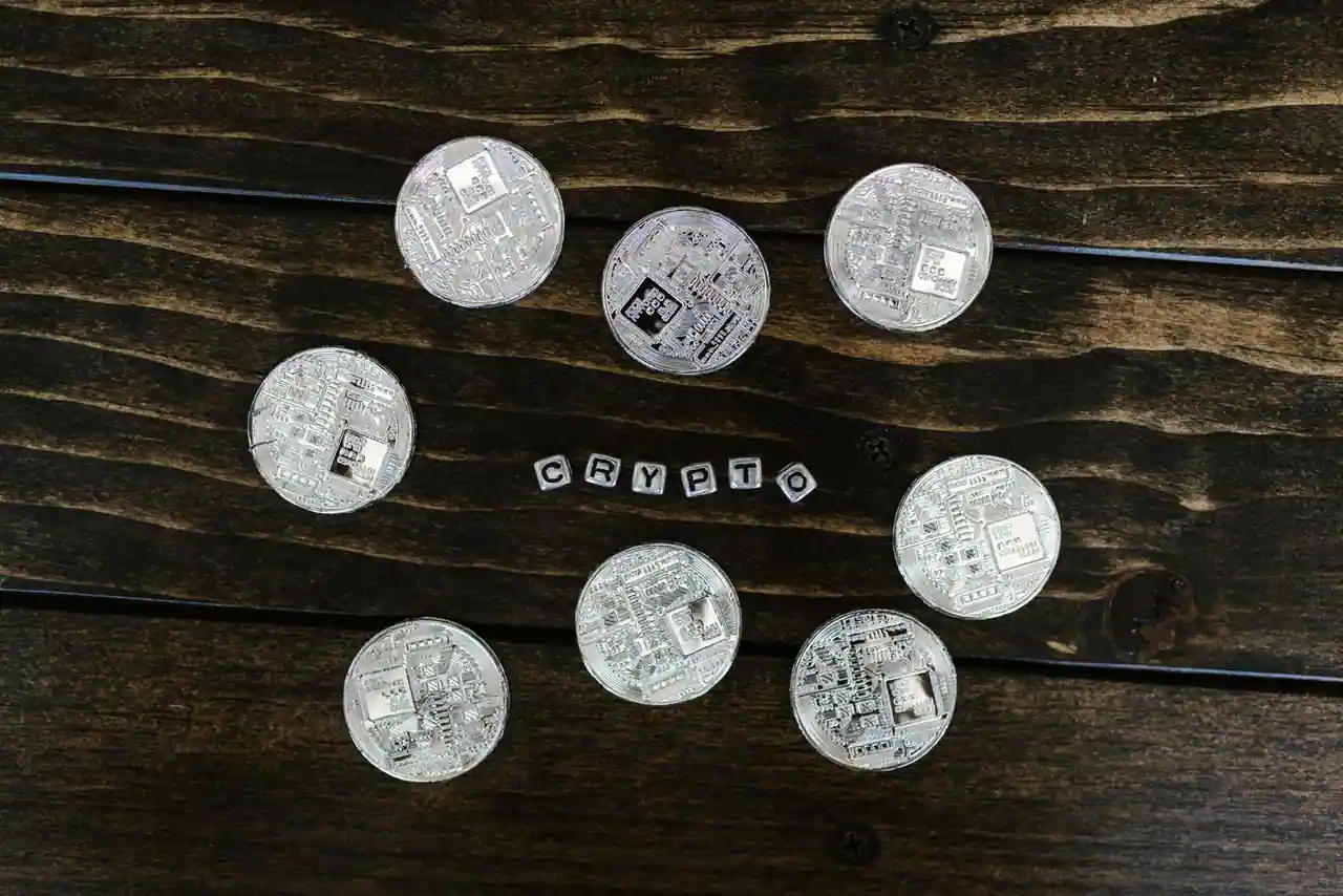Jetons métalliques sans marque disposés autour de lettres formant le mot crypto sur un plateau en bois